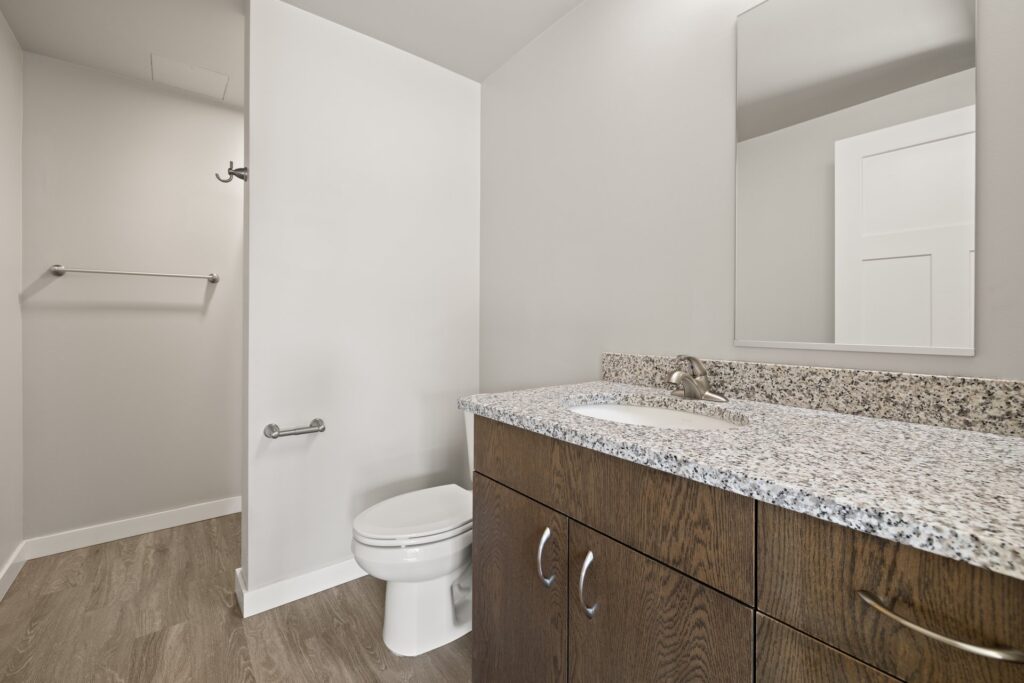 bathroom with granite countertops, wall mirror, single sink, and wood-style flooring